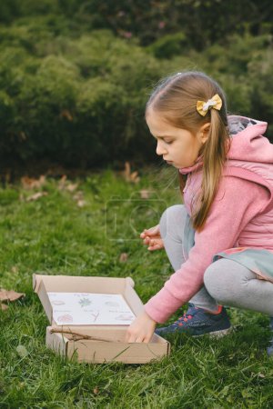 Foto de Búsqueda de carroñeros para niños en el parque. Chica aprendiendo sobre el medio ambiente. Actividad educativa natural para el Día Mundial de la Tierra. Explorando en primavera. - Imagen libre de derechos
