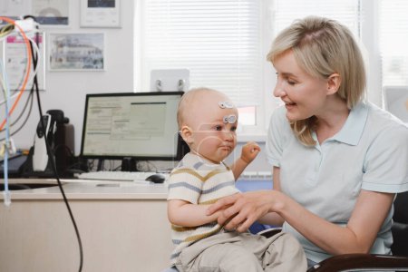 Téléchargez les photos : Femme avec enfant consultant un médecin pour un bilan auditif. Parent avec enfant en bas âge audiologiste visiteur. Mère avec bébé au cabinet médical ou à l'hôpital - en image libre de droit