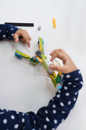 Photo for Coding Class, school girl constructing robot arm mechanism. multiethnic children making science, technology tasks with tablet. Modern education African American girl experimenting on lesson Close-up - Royalty Free Image
