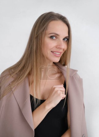 Photo for Gentle Caucasian woman in bodysuit and business jacket Daring fashion style portrait of decisive strong female. Minimalism. sensual cheerful free person, blonde hair taking off clothes over white wall - Royalty Free Image
