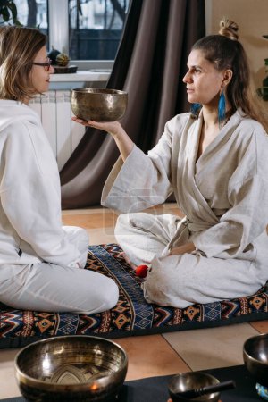 Photo for Sound healing with singing bowls, vibration massage and alternative therapy. Mental health care, meditation and relax. Therapist playing to old mature woman in 60s. singing, meditating practice - Royalty Free Image