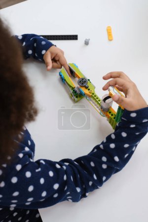 Photo for Coding Class, school girl constructing robot arm mechanism. multiethnic children making science, technology tasks with tablet. Modern education African American girl having fun experimenting on lesson - Royalty Free Image