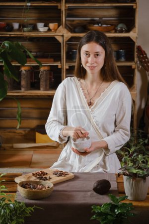 Photo for Cacao ceremony in atmospheric space with green plants and candles. Woman making ritual healthy drink from cocoa beans - Royalty Free Image
