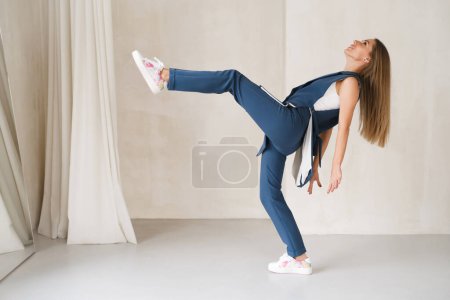 Photo for Creative balancing young woman ready to step or fall. Happy in business costume. Daring fashion style portrait of decisive strong female in light room. Modern supernatural trendy - Royalty Free Image