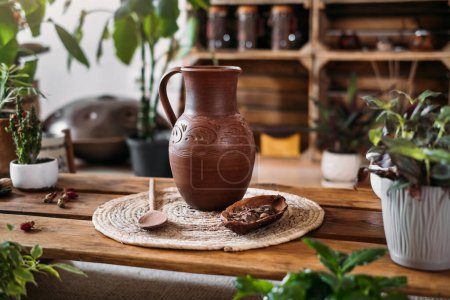 Photo for Jug with hot organic cacao for ceremony, closeup. Healthy drink from raw cocoa beans in green vegetarian cafe Copy space, ritual for harmony in green rustic place - Royalty Free Image