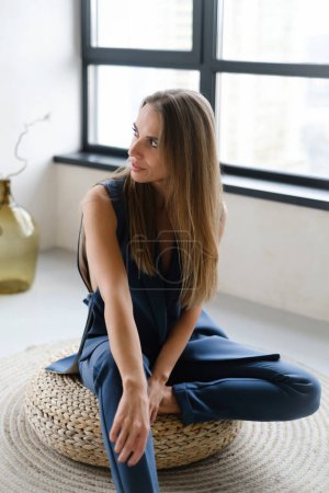 Photo for Pretty gentle Caucasian woman happy in smart casual business costume. Daring fashion style portrait of strong female in light sunny room with window. Modern energetic young girl moving in blue - Royalty Free Image