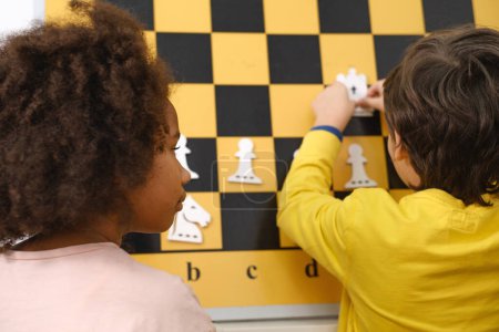 Téléchargez les photos : Gros plan Enfant Penser dur sur les échecs Combinaisons sur le tournoi pour les enfants Jeu intellectuel, passe-temps pour les enfants de dos - en image libre de droit
