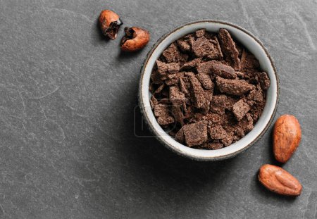 Photo for Chocolate crumbs in bowl ready for cooking top view. Organic fermented or raw cacao beans for hot drinks. Flat lay with copy space for recipe. Ingredients for sweet food - Royalty Free Image