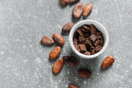 Cacao beans on grey concrete background. Raw fermented. organic cocoa seeds for hot chocolate drink. Flat lay, copy space for food and drink recipe. Healthy nibs