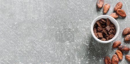 Foto de Banner Frijoles de cacao sobre fondo de hormigón gris. Crudo fermentado. semillas de cacao orgánico para la bebida de chocolate caliente. Colocación plana, espacio de copia para la receta de alimentos y bebidas. Plumas sanas - Imagen libre de derechos