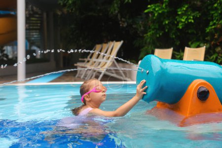 Téléchargez les photos : Enfant jouant dans un parc aquatique. Enfant s'amusant et divertissant dans la piscine intérieure. Tout-petit fille faire des éclaboussures avec saupoudrer - en image libre de droit