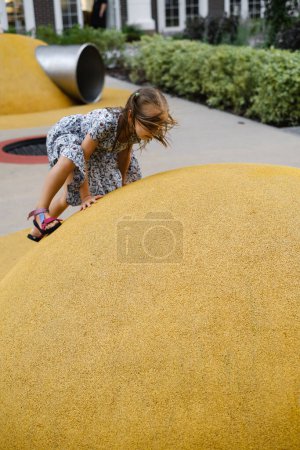 Téléchargez les photos : Enfant jouant sur une aire de jeux en ville. Une fille qui court. Les enfants d'âge préscolaire s'amusent dehors en été. Développer la coordination - en image libre de droit