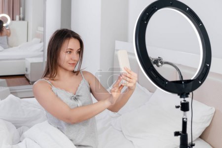 Foto de Female Blogger Recording Vlog Video on smartphone At Home Online Influencer On near bed. Streaming belleza bloger - Imagen libre de derechos
