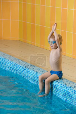 Foto de Niño pequeño aprendiendo a bucear en la piscina cubierta con el maestro. De pie al lado, equilibrio y actividad física general para los niños en el agua, desarrollo temprano. Niño niño instruido - Imagen libre de derechos