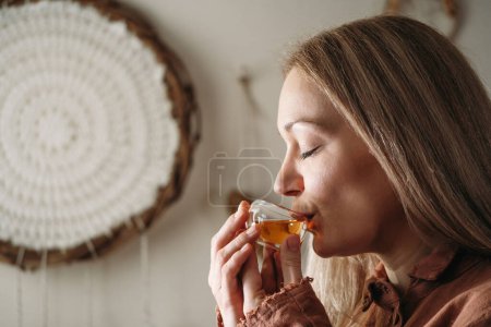 Women preparing tea ceremony in boho style atmospheric room with plants in studio. Transparent tea cups with warm drink in hands. Aroma of traditional Oolong Chinese drink