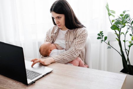 Photo for Working and breast feeding woman with infant on her hands near laptop at home over the window. Studying on-line mother near computer with baby boy. Working from home mom with child - Royalty Free Image