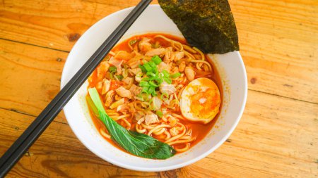 A bowl of Spicy Tori Paitan Miso Ramen noodle soup with beef, egg, and vegetable.