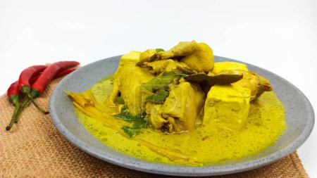 Opor Ayam, comida tradicional indonesia servida en un plato gris, hecha de pollo cocinado con leche de coco y especias. Normalmente se sirve para celebrar Eid Adha y Eid Fitr.