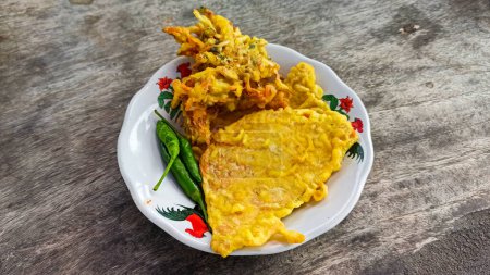 Bakwan Sayur or Bala-bala or Ote-ote are vegetable fritters and mendoan or fried tempe with cayenne on plate. Delicious snack in Indonesia.