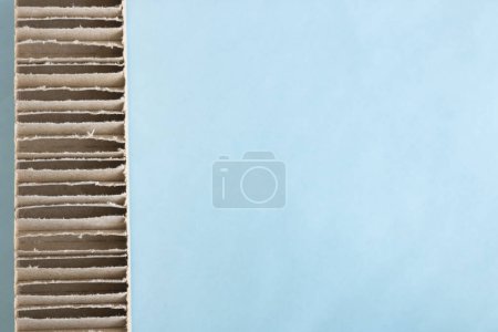 Téléchargez les photos : Bande de carton ondulé située sur le côté gauche de l'image sur un fond bleu. espace pour écrire. horizontal. - en image libre de droit