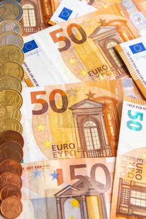 Téléchargez les photos : Pile de billets de cinquante euros et une rangée de pièces en euros sur le côté droit de l'image. photographie verticale - en image libre de droit