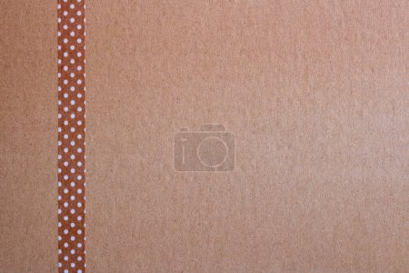 Téléchargez les photos : Fond de papier brun artisanal et une bande de ruban brun artisanal avec de petits points blancs sur le côté gauche de l'image - en image libre de droit