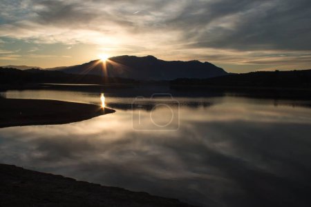 Foto de Gran exposición de las puestas de sol sobre el embalse de Beniarrs con reflejos en el agua de las nubes - Imagen libre de derechos