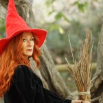 Redhead witch with red hat and broom looking at camera in the preventory of Alcoi, Spain