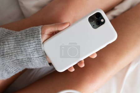 Photo for Close-up of female hands holding smartphone with on bed - Royalty Free Image