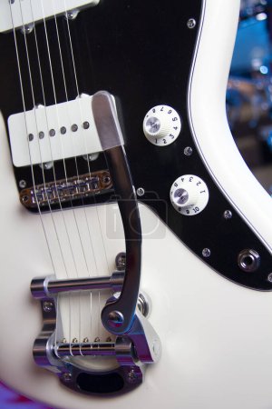Foto de Primer plano de una guitarra eléctrica blanca sólida con pastillas humbucker, pickguard negro, puente flotante con palanca vibrato y hardware de plata. - Imagen libre de derechos