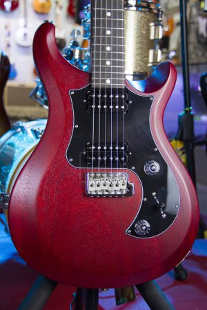 Foto de Primer plano de una guitarra eléctrica roja sólida con pastillas humbucker, pickguard negro y hardware de plata. - Imagen libre de derechos