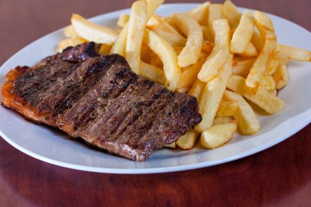 Photo for Fried beef steak with french fries on a wooden plate - Royalty Free Image