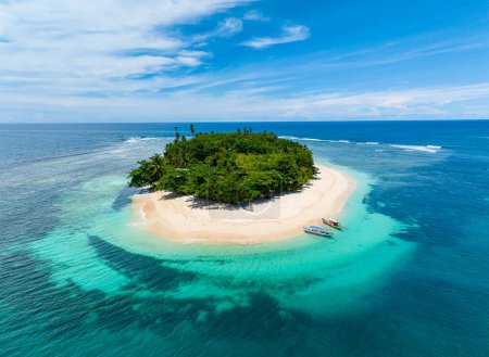 Isla de San Víctor con playa de arena blanca bajo cielos azules y nubes. Atolón de agua turquesa y arrecifes de coral. Mindanao, Filipinas. Concepto de verano y viajes.
