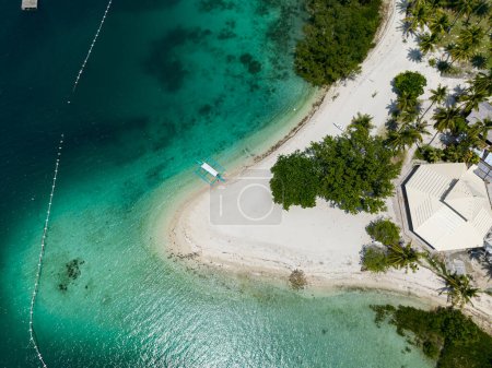Isla tropical con playa de arena blanca y palmeras. Agua y olas transparentes con reflejo de la luz solar. Isla Malipano. Samal, Davao. Filipinas.