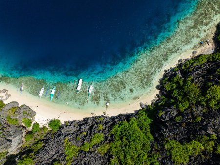 Téléchargez les photos : Vue de dessus de la plage de Talisay et des bateaux flottant au-dessus du porteur de mer clair. L'île Tapiutan. El Nido, Philippines. - en image libre de droit
