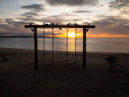 Swing on sandy beach with ocean waves and sunset background. Santa Fe, Tablas, Romblon. Philippines.