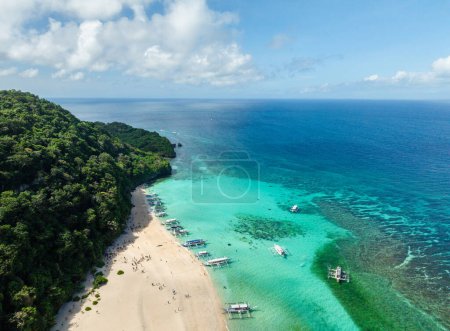 Meereswellen auf weißem Sand, Boote, die über klarem türkisfarbenem Wasser schwimmen. Puka Shell Beach. Boracay, Philippinen.