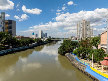 River between residential area in Metro Manila. Blue sky and clouds. Philippines.