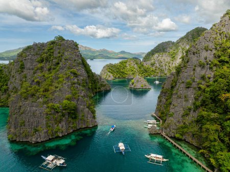 Boats over green water surrounded by splendid limestone rocks in islands. Kayangan Lake. Coron, Palawan. Philippines.