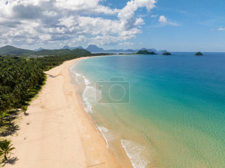 Coconut trees and clear water and waves on Nacpan Beach. El Nido, Palawan. Philippines.