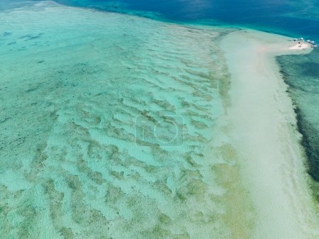 Agua de mar turquesa con fondo oceánico de arena blanca. Sandbar con barcos y olas. Surigao del Sur, Filipinas.
