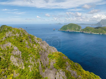 Aerial view of Inambuyod Island from Matinloc. Blue sea, blue sky and clouds. El Nido, Philippines.