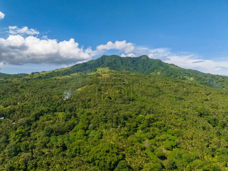 Montaña verde con exuberante bosque verde y selva. Cielo azul y nubes. Isla Camiguin. Filipinas.