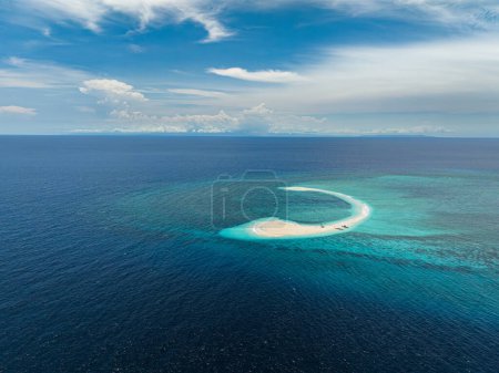 Aerial survey of Sandbank surrounded by turquoise water and corals. Blue sky and clouds. Camiguin Island, Philippines.