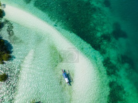 Vista superior del barco flotando sobre el agua turquesa transparente. Samal, Davao. Filipinas.