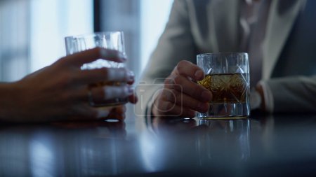 Business partners hands drinking whiskey in restaurant closeup. Unknown colleagues spending time with bourbon beverages in fancy place. Rich entrepreneurs holding expensive alcoholic drink glasses
