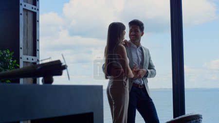 Téléchargez les photos : People in love flirting touching sea view luxury hotel. Romantic couple dating against ocean panoramic window. Stylish rich man holding wife hands tenderly at marina landscape room. Love concept - en image libre de droit