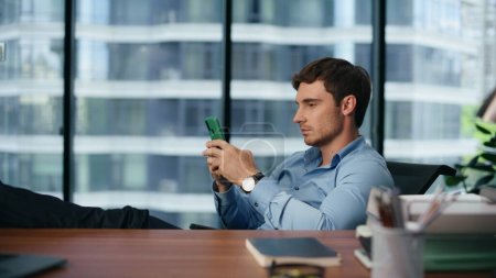 Serious boss working smartphone in panoramic place. Focused businessman using cellphone in modern office. Thoughtful employee texting message mobile phone at luxury workplace. Technology concept 