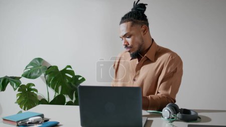 Foto de Serious businessman answering mobile in office closeup. Dreadlocks worker talking smartphone call at home. Confident man picking up cellphone chatting with client. African american guy working alone - Imagen libre de derechos
