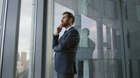 Photo for Serious smart entrepreneur lost in thoughts searching problem solution new ideas standing at office window. Bearded businessman pondering on important decision. Pensive manager contemplating failure. - Royalty Free Image
